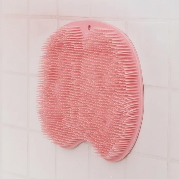 Close-up of a pink silicone multiuse scrubber, highlighting its durable texture and flexible bristles against a blush pink ba